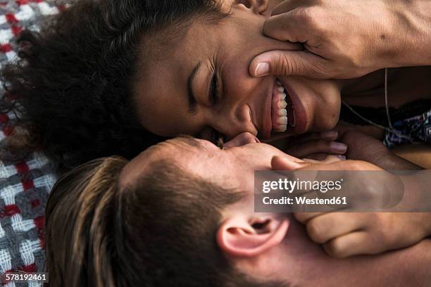 intimate young couple lying on blanket - touching face stock pictures, royalty-free photos & images