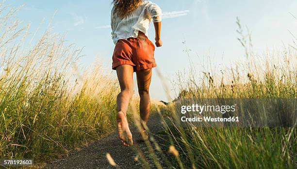 young woman running on path in field - bare feet stock pictures, royalty-free photos & images