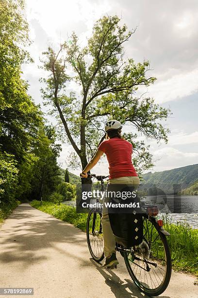 germany, cochem, woman riding bycicle along riverside of moselle - moseltal stock pictures, royalty-free photos & images