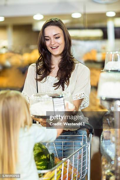 mother and daughter with shopping trolley buying cake - supermarket trolley female stock-fotos und bilder