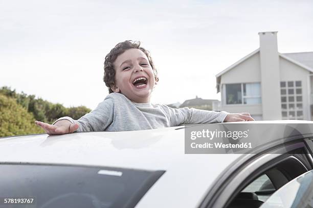 happy boy looking through a sunroof of a car - car roof stock pictures, royalty-free photos & images