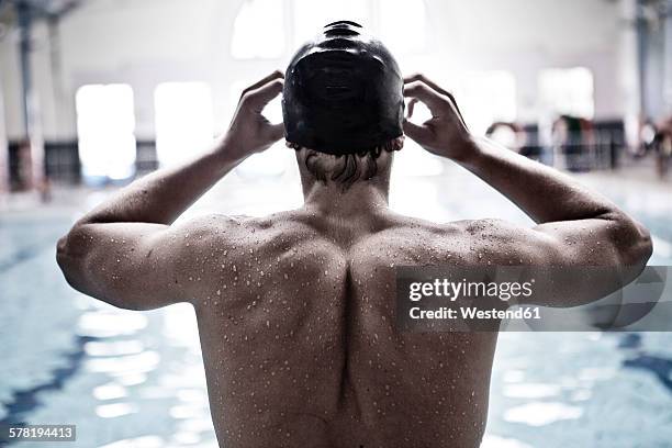 swimmer in indoor pool putting on swimmming goggles - beginnings stock-fotos und bilder