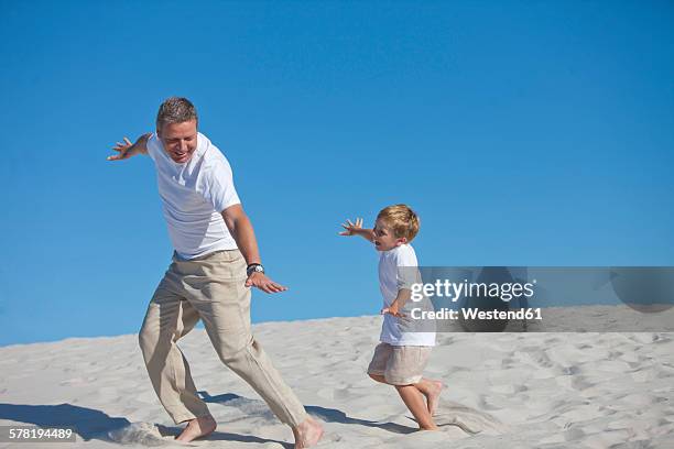 playful father and son in sand - 飛行機のまね ストックフォトと画像