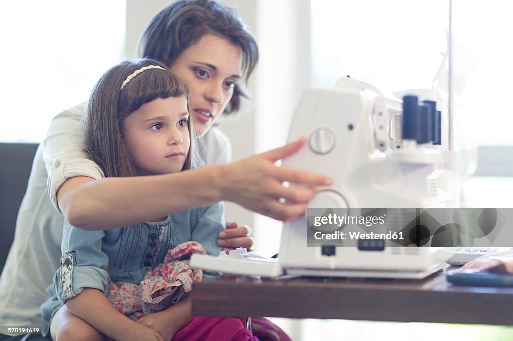Mother and daughter sewing clothes at home