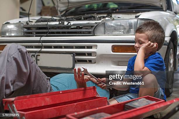 son helping father in home garage working on car - car toolbox stock pictures, royalty-free photos & images