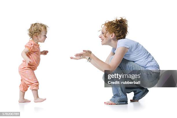 profile of a baby girl reaching for her mother - girls barefoot in jeans stockfoto's en -beelden