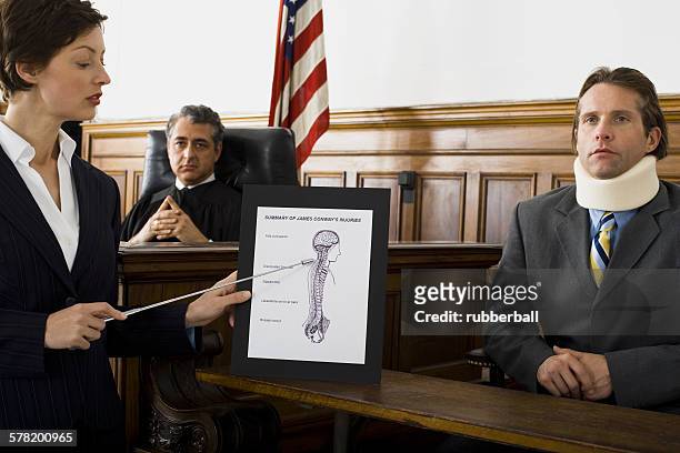 female lawyer pointing at an exhibit in front of a judge and a victim - court notice stock pictures, royalty-free photos & images