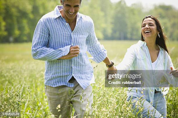 man and a woman holding hands and running in a field - gestreift fotografías e imágenes de stock