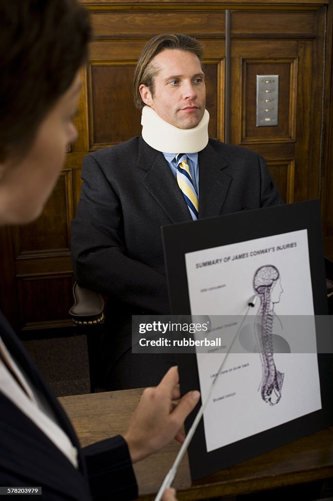 A female lawyer pointing at evidence in front of a victim in a courtroom