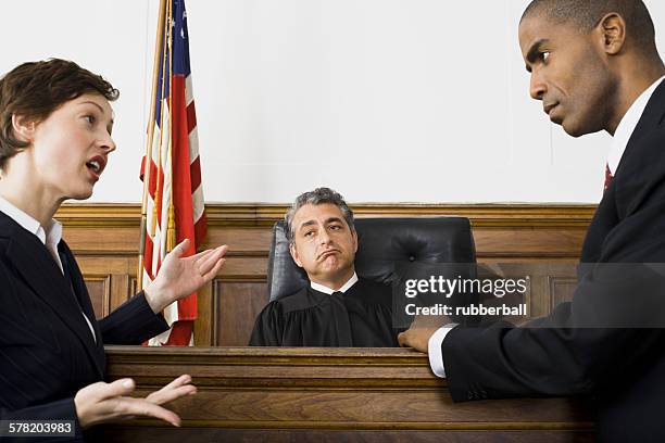 two lawyers standing face to face in front of a male judge in a courtroom - åklagare bildbanksfoton och bilder