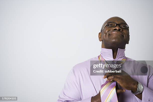 portrait of a businessman tying his tie - rayado photos et images de collection