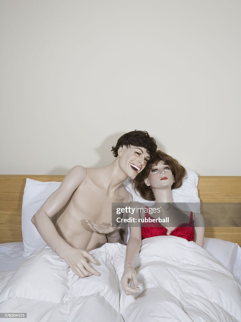 Male mannequin and a female mannequin reclining on the bed and laughing