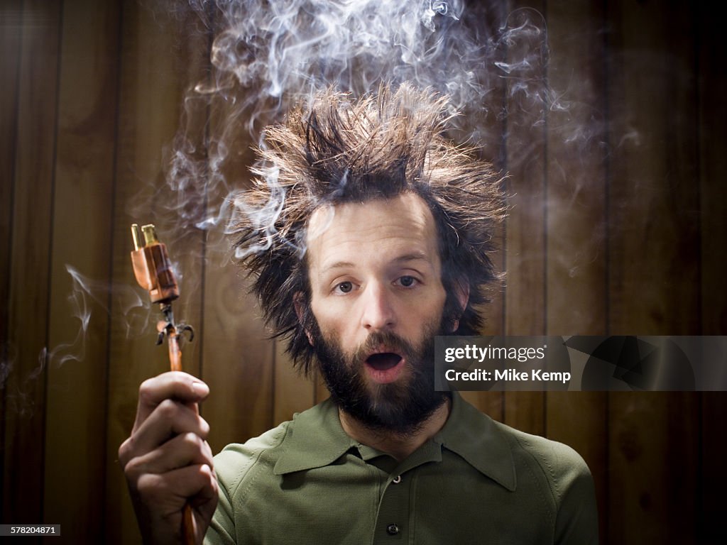 Man after electric shock with electric plug and smoke