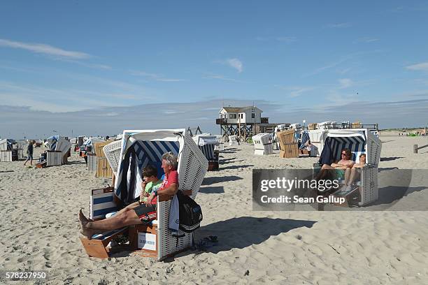 Visitors, including a father and son who said they did not mind being photographed, relax in beach chairs at the beach on July 18, 2016 at...