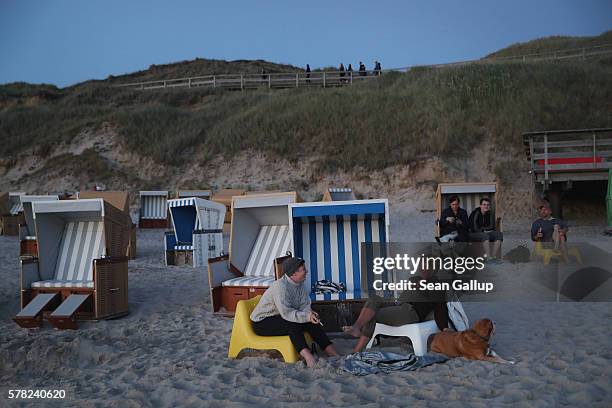 Visitors, including two women with a dog who said they did not mind being photographed, relax among beach chairs next to dunes at a beach after...