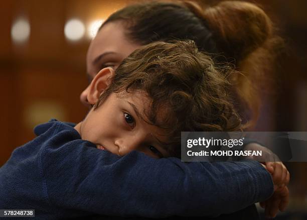 Nicolette Gomes , daughter of Jacquita Gomes, carries Raphael Ariano , grandson of Patrick Gomes, inflight supervisor on the missing Malaysia...