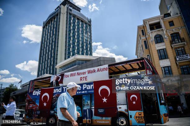 Man walks past a sightseeing bus covered with Turkish national flags and a poster of Turkish President Recep Tayyip Erdogan on July 21, 2016 on...