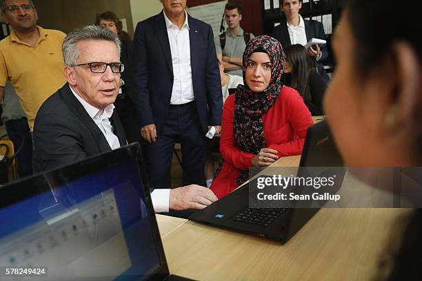 German Interior Minister Thomas de Maiziere chats with trainees in an accounting class at the BWK job training center on July 21, 2016 in Berlin,...