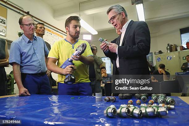 German Interior Minister Thomas de Maiziere chats with a trainee in a systems mechanics class at the BWK job training center on July 21, 2016 in...