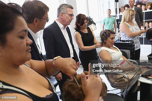 German Interior Minister Thomas de Maiziere chats with trainees in the hair salon at the BWK job training center on July 21, 2016 in Berlin, Germany....