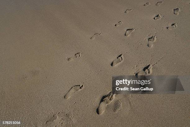 Incoming waves wash away footprints left by visitors in the sand along a beach on Sylt Island on July 19, 2016 near Wenningstedt, Germany. Sylt...