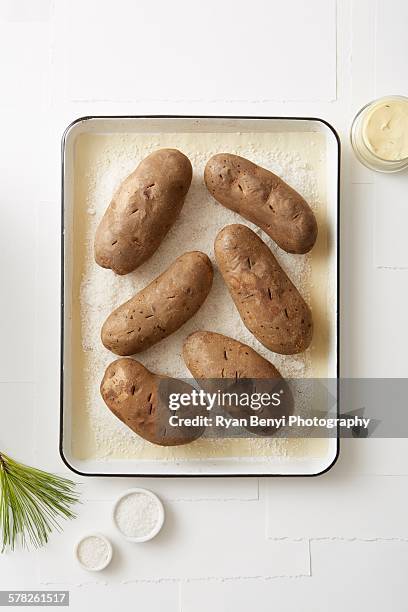 still life of salt baked potatoes in roasting tin - baked potato stock pictures, royalty-free photos & images