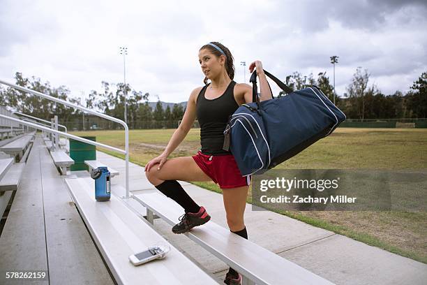 soccer player placing sports bag on bench - athleticism stock pictures, royalty-free photos & images
