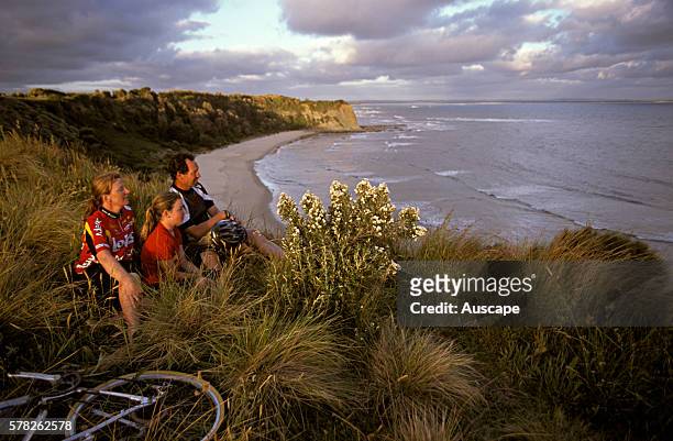 Family on a bike ride watching sunset from cliff top near Inverloch, Gippsland, Victoria, Australia.