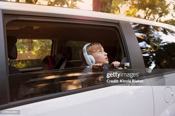 boy wearing headphones gazing out of car window - car listening to music imagens e fotografias de stock