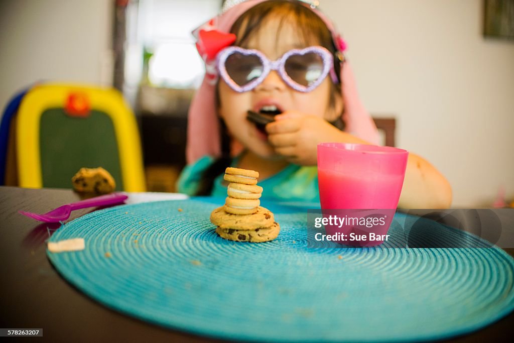 Young girl sitting at table with drink and cookies