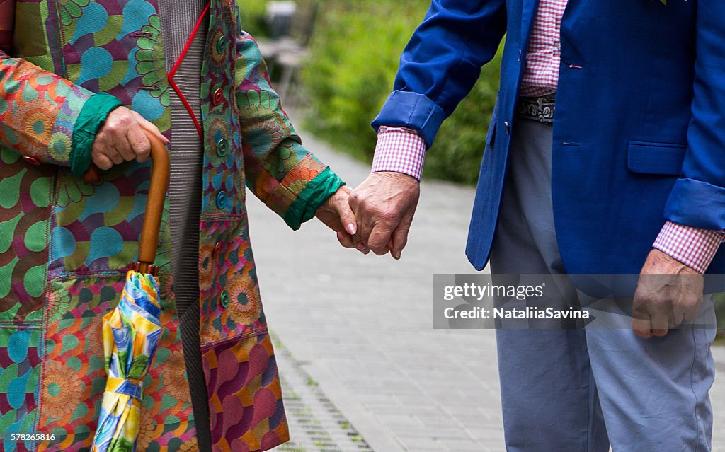 Elderly man and an elderly woman holding hands.