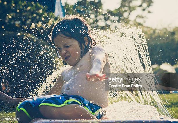 young boy playing in a slip and slide. - backyard water slide stock pictures, royalty-free photos & images