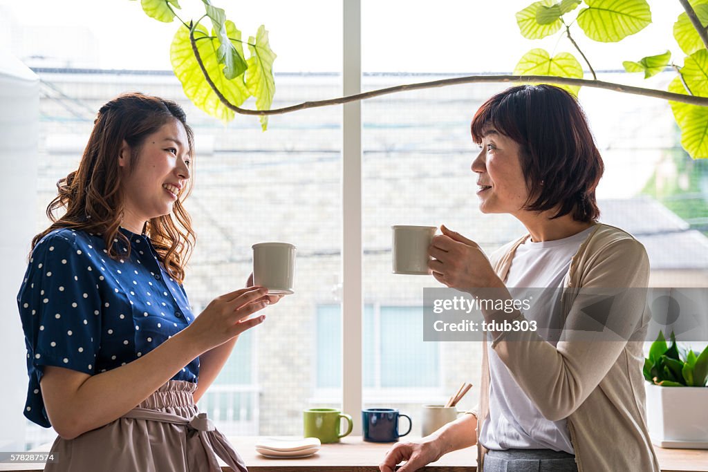 Mid adult daughter and senior mother talking while having coffee