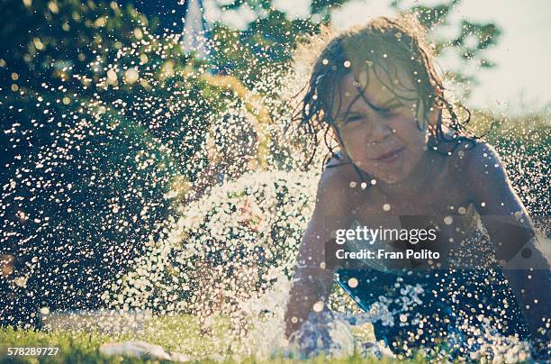 boy playing in the slip and slide. - backyard water slide stock pictures, royalty-free photos & images