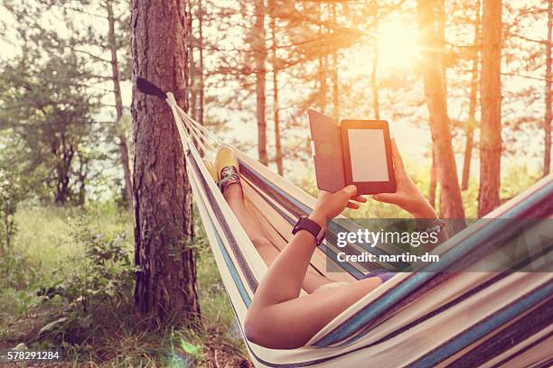 chica joven en una hamaca y libro electrónico - lector de libros electrónicos fotografías e imágenes de stock