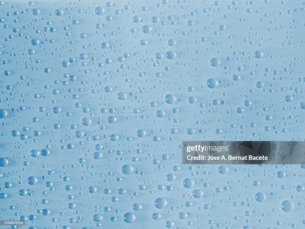 Background, water drops on a surface of light blue glass