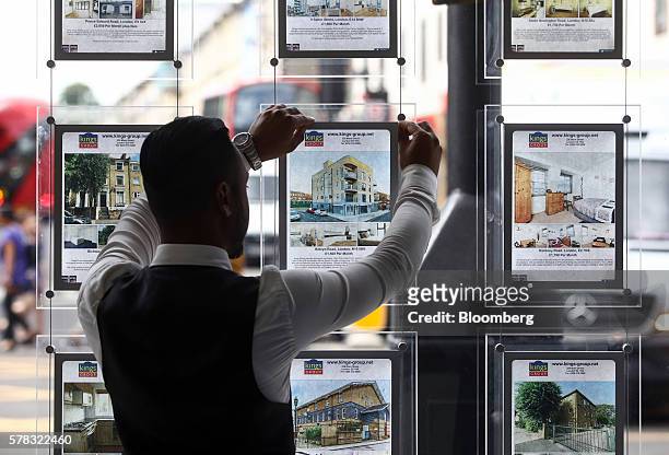 An employee places an advert for a residential house for sale into an estate agent's window in this arranged photograph in the Hackney borough of...