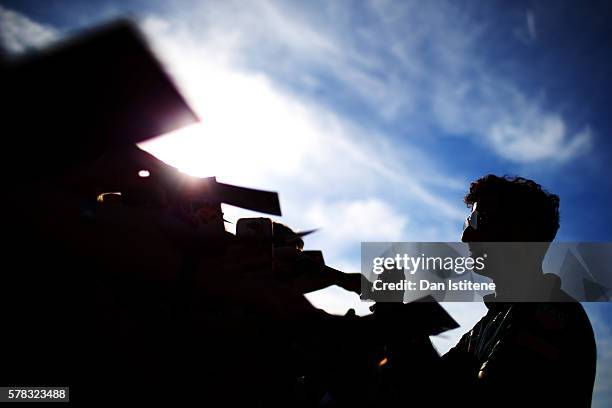 Daniel Ricciardo of Australia and Red Bull Racing signs autographs for fans in the pit lane during previews ahead of the Formula One Grand Prix of...