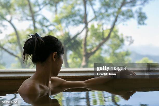 a young backless woman bathing at hot spring resort with beautiful landscape view - onsen japan stock pictures, royalty-free photos & images