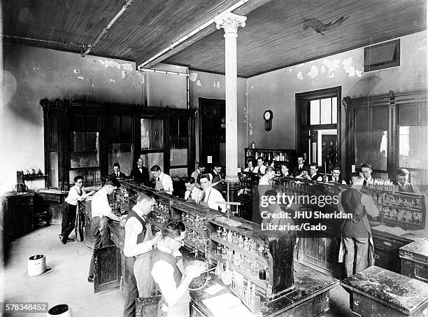 Male Chemistry students working in a laboratory in a Chemistry building from the Old Campus of Johns Hopkins University, lined up at benches with...