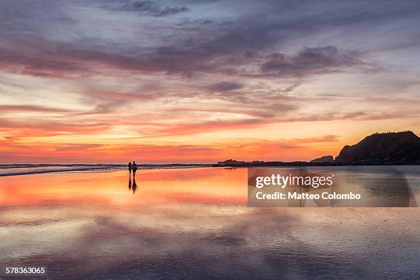 couple walking on beach at sunset, costa rica - nosara costa rica stock pictures, royalty-free photos & images