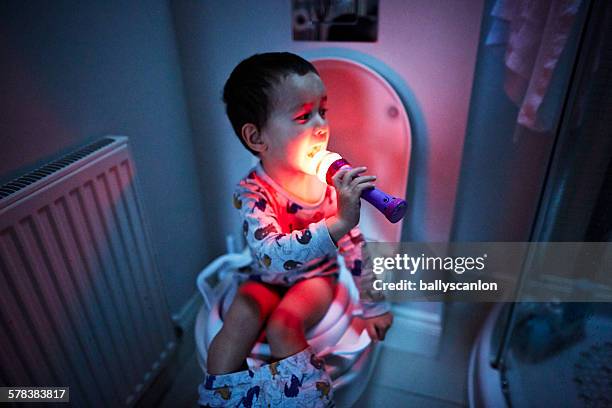 boy singing into microphone on toilet - bathroom night stockfoto's en -beelden