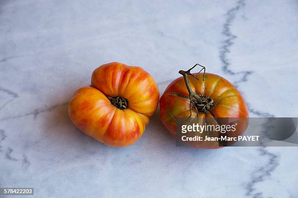 true organic tomatoes "beef heart" on a marble tab - jean marc payet stockfoto's en -beelden