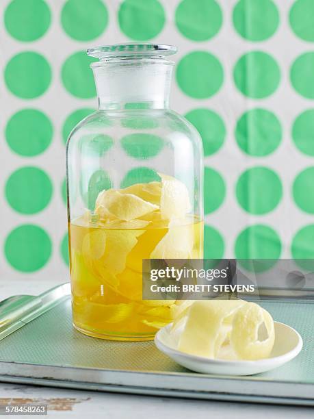 lemon peel infusing in large glass jar to make lemon iced tea - zitruszeste stock-fotos und bilder