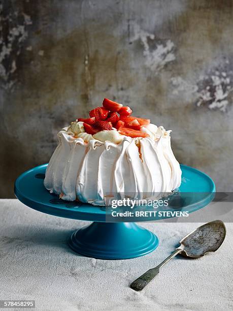 strawberry covered pavlova on blue ceramic cake stand with cake server - cake stand stock pictures, royalty-free photos & images