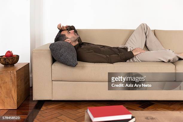 side view of mature man lying on back on sofa hand on forehead, looking up - auf dem rücken liegen stock-fotos und bilder