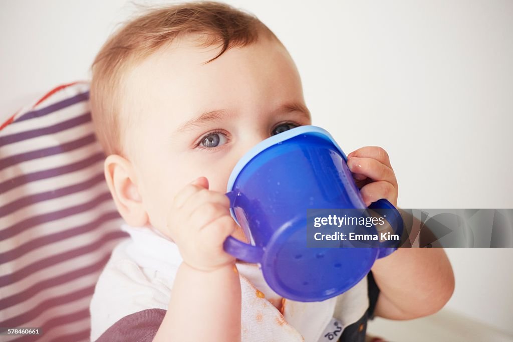 Baby boy drinking in baby chair