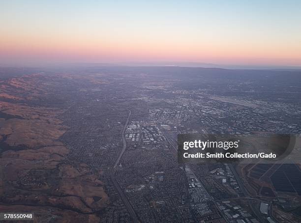 Aerial view of Silicon Valley at dusk, including the towns of Milpitas, Santa Clara, and San Jose, with the Mineta San Jose International Airport...