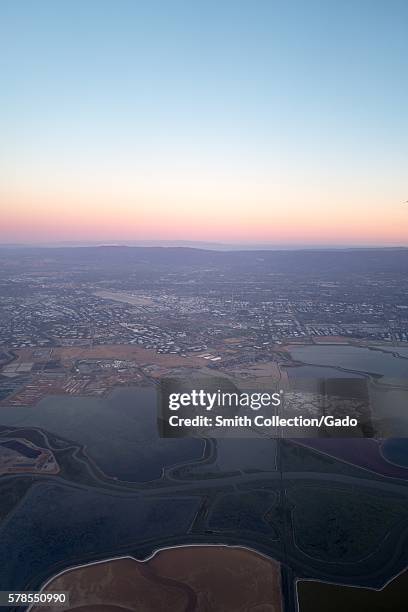 Aerial view of Silicon Valley at dusk, including salt ponds on the San Francisco Bay and the towns of Santa Clara and San Jose, with Levi Stadium...