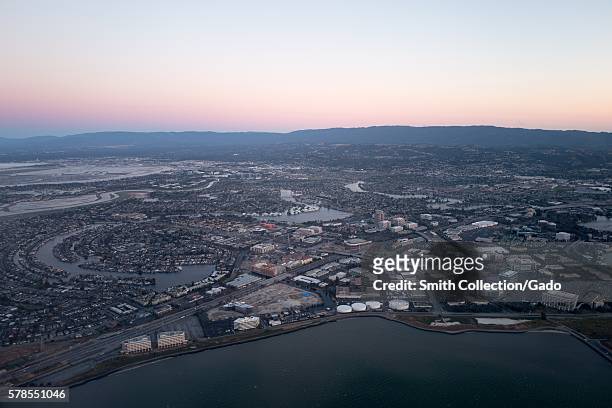 Aerial view of Silicon Valley at dusk, with a portion of the San Mateo/Hayward Bridge visible, as well as Foster City, including the California...